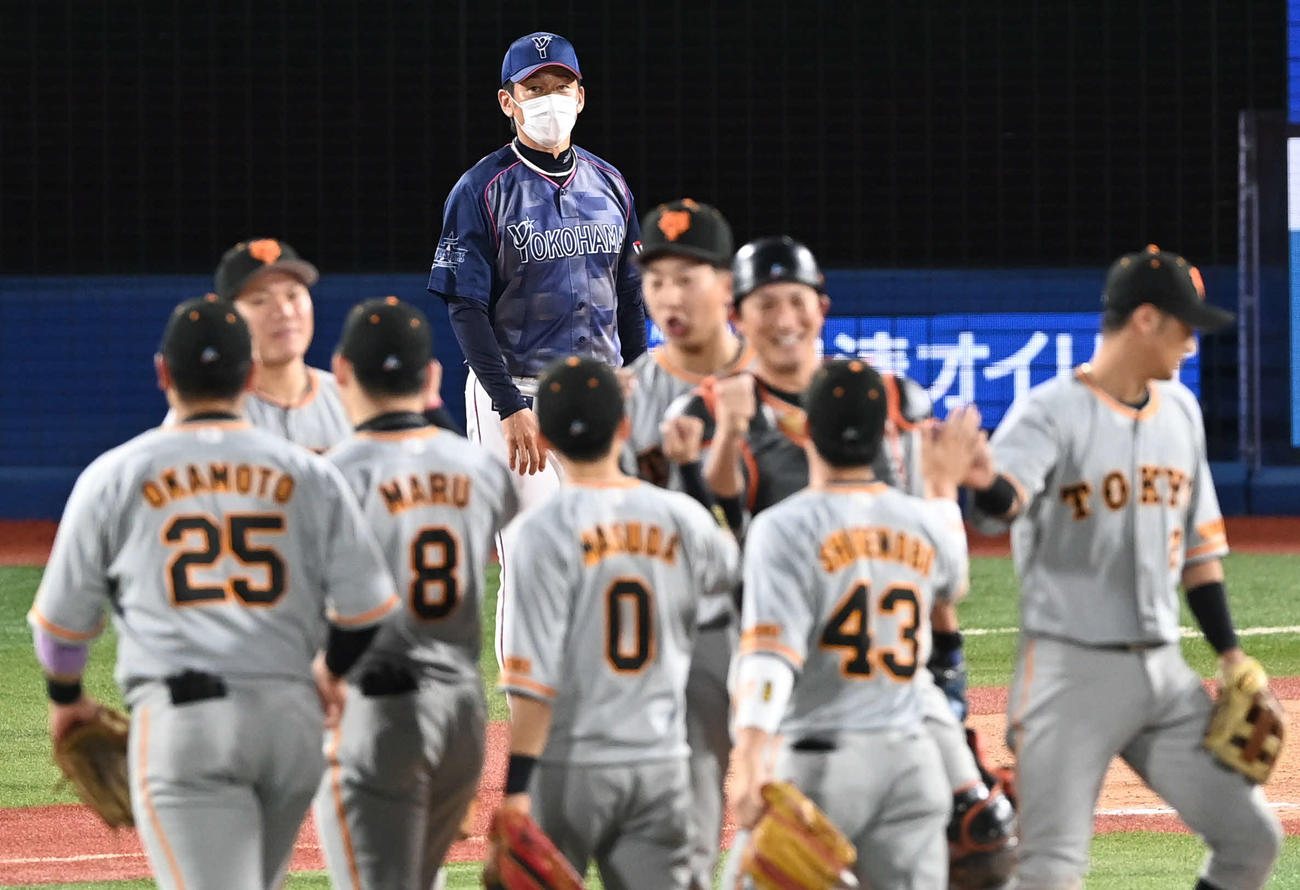DeNA対巨人　DeNA三浦監督（後方）は勝利に喜ぶ巨人の選手を見つめる（撮影・山崎安昭）