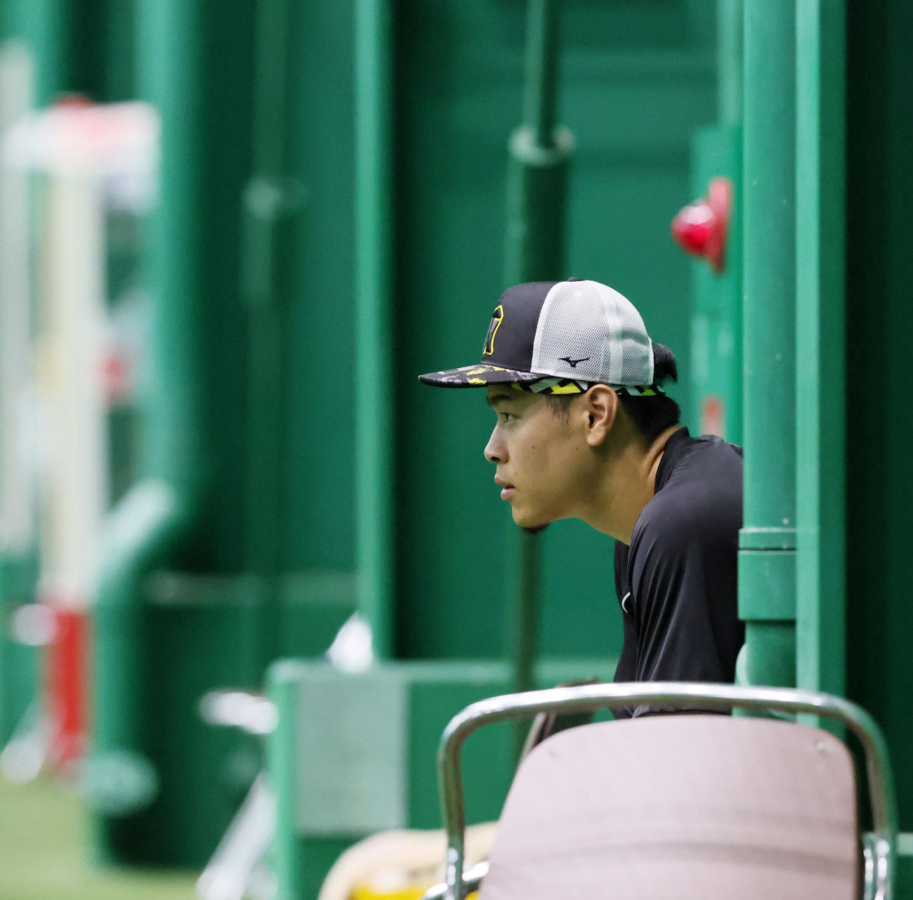 練習中、室内練習場の椅子に座ってナインの動きを見つめる佐藤輝（撮影・加藤哉）