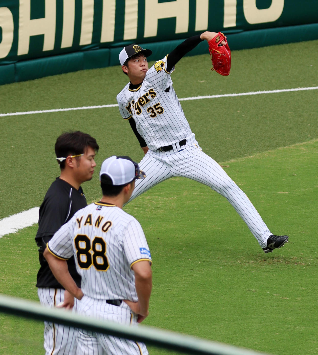 西勇（左）と話す矢野監督の前でキャッチボールする才木（撮影・加藤哉）