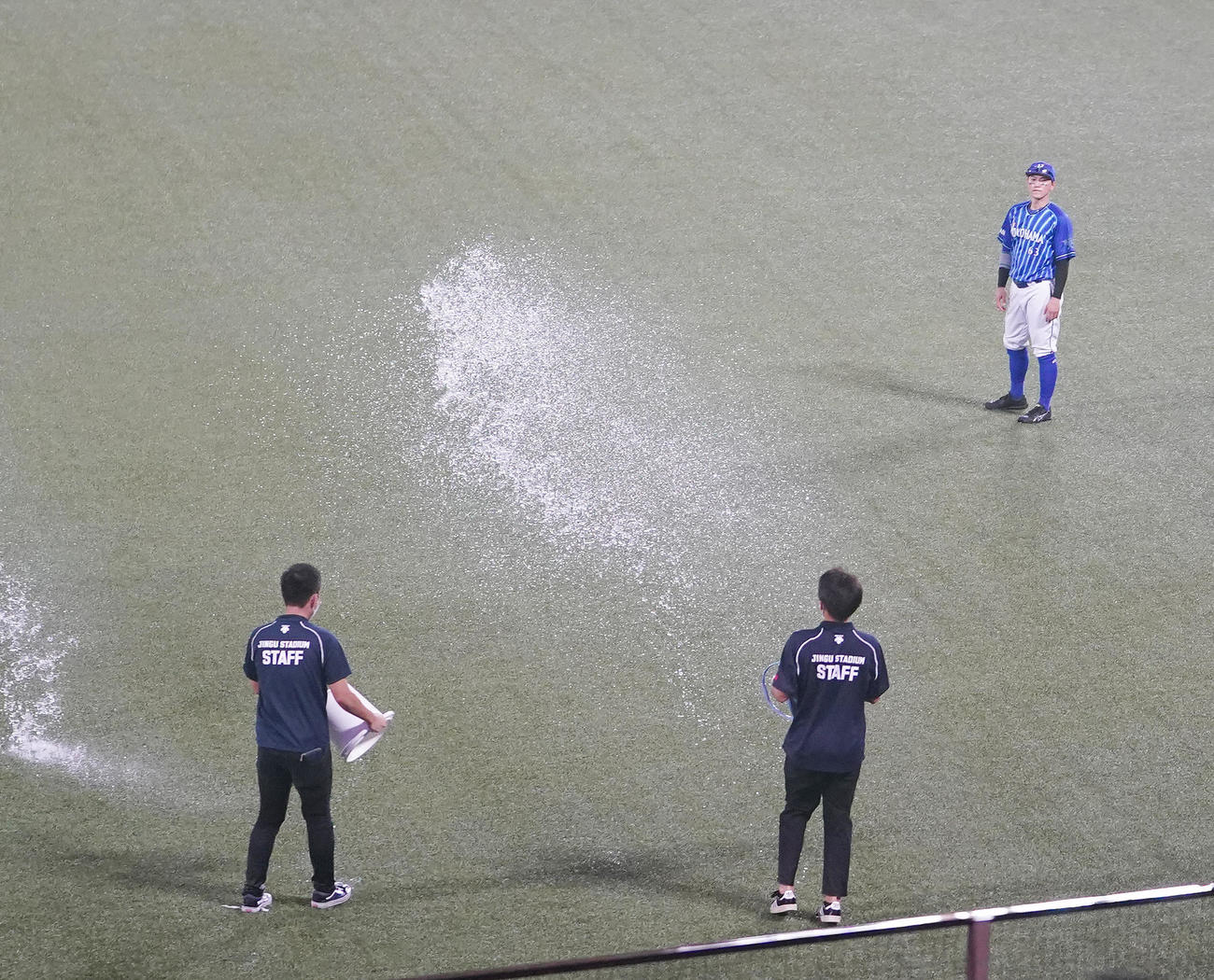 ヤクルト対DeNA　外野の水たまりの水をバケツでまくスタッフを見るDeNA関根（撮影・鈴木みどり）