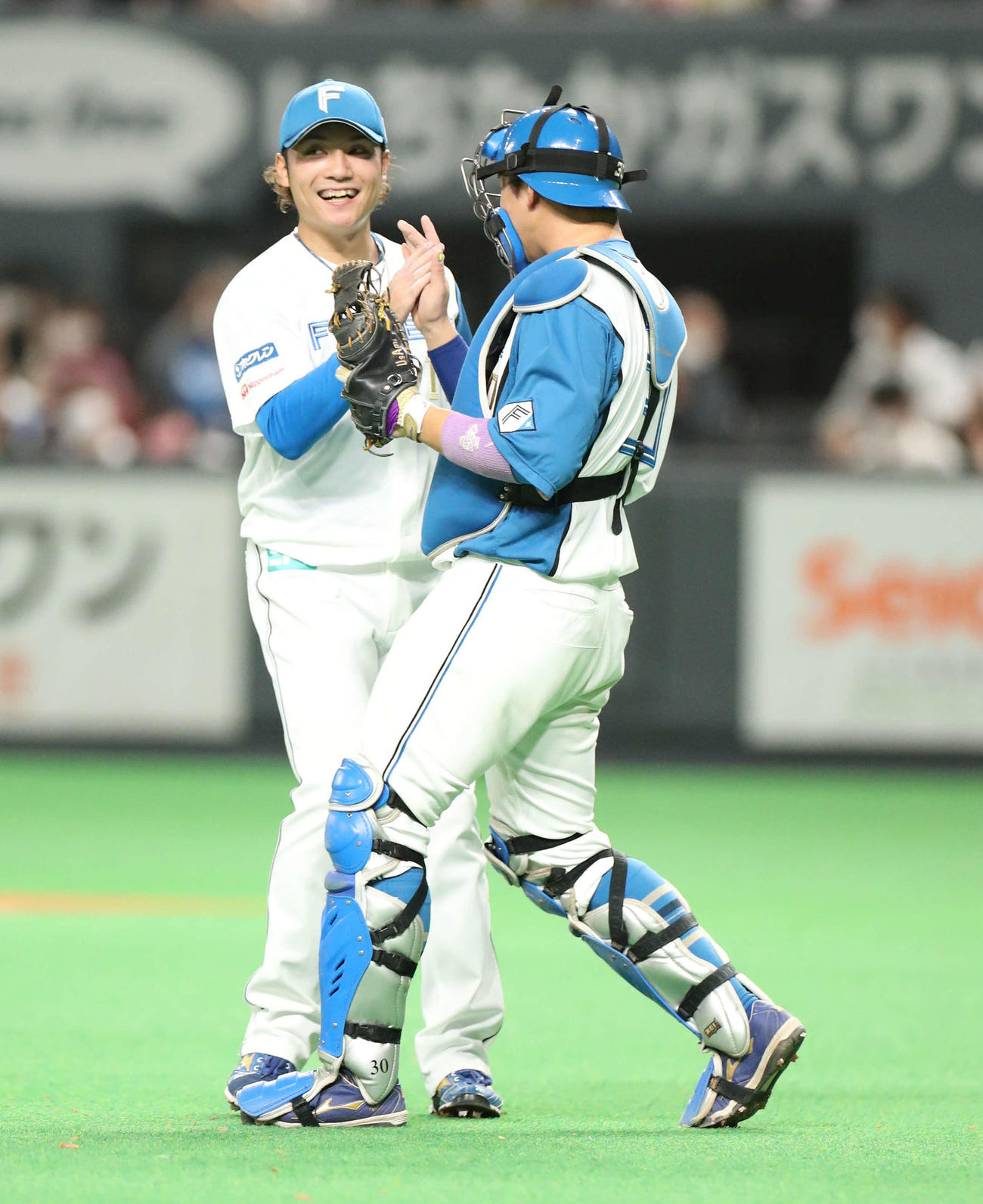 日本ハム対楽天　プロ初セーブを挙げた日本ハム伊藤（左）は宇佐見とタッチを交わす（撮影・佐藤翔太）