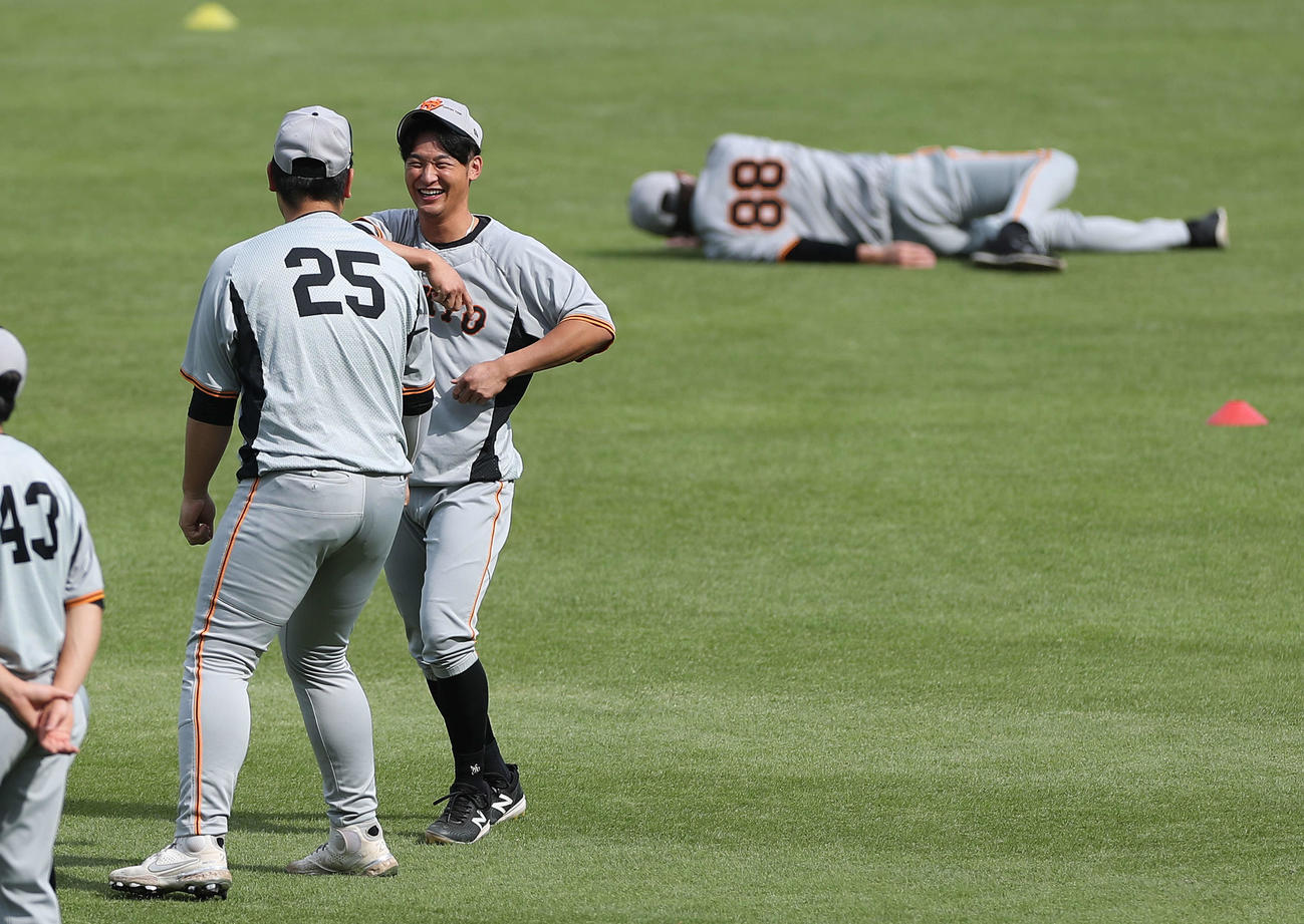 練習開始前、笑顔で言葉を交わす巨人岡本和（左）と吉川（撮影・河田真司）