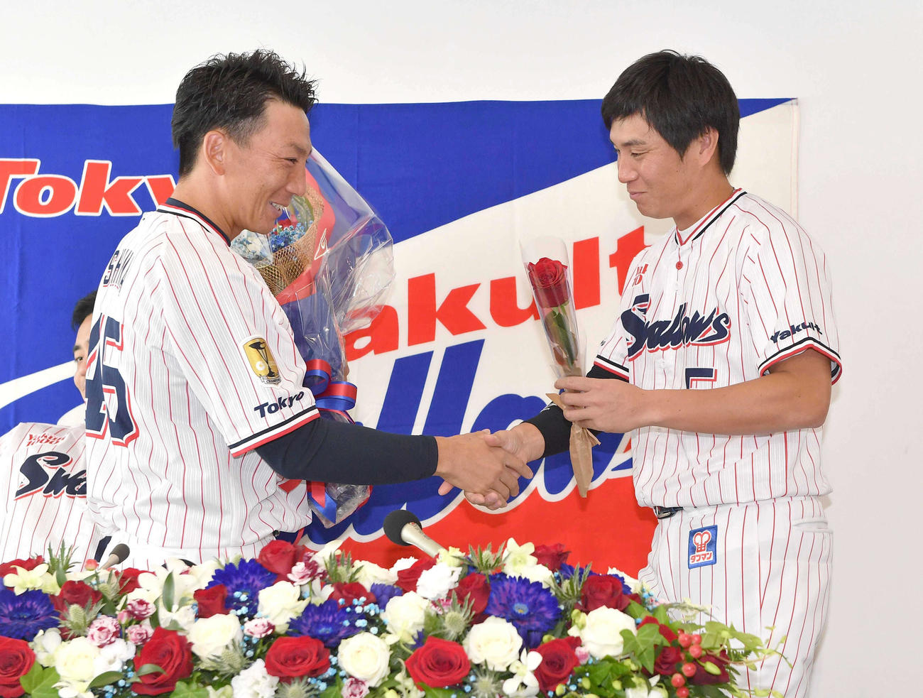 川端（右）から笑顔で花束を受け取るヤクルト嶋（代表撮影）