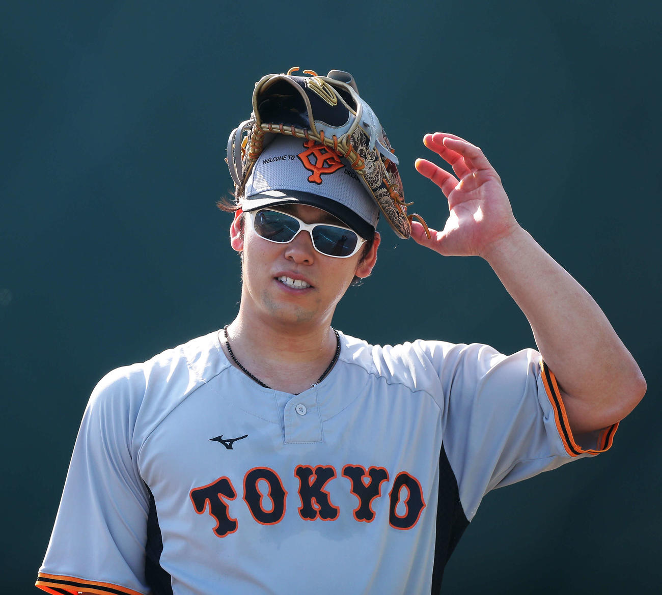 グラブを頭に乗せる巨人高梨（撮影・河田真司）