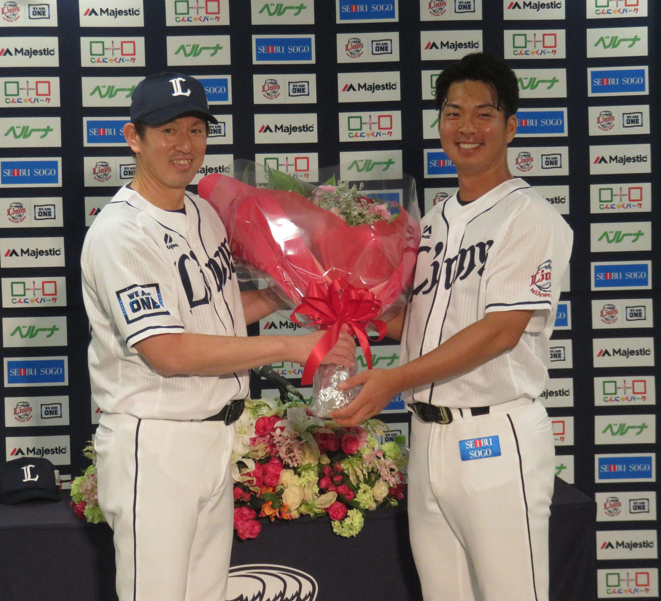 引退会見で豊田投手コーチ（左）から花束を受け取る西武十亀