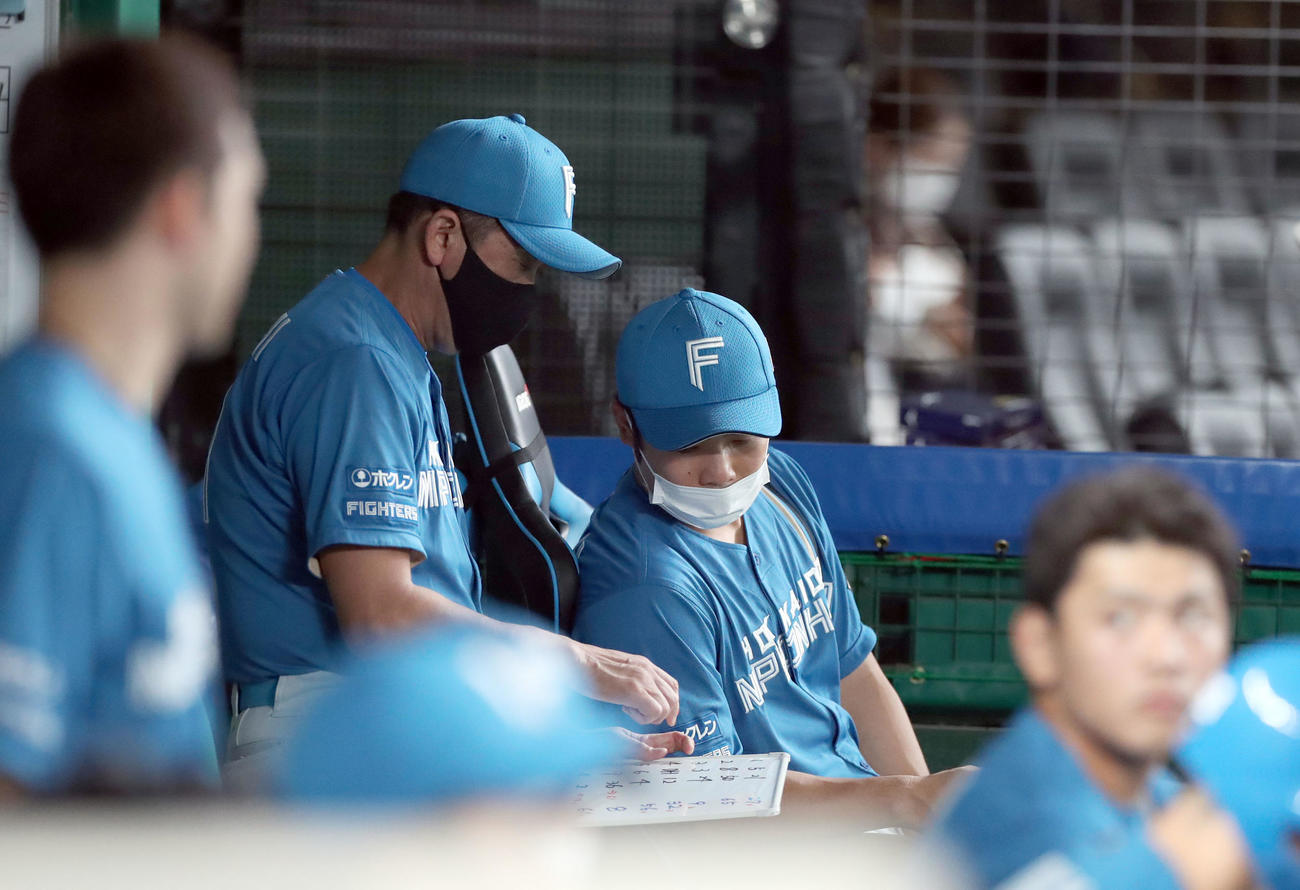 西武対日本ハム　監督席に座りながら林ヘッドコーチ（左）と話す近藤（撮影・佐藤翔太）