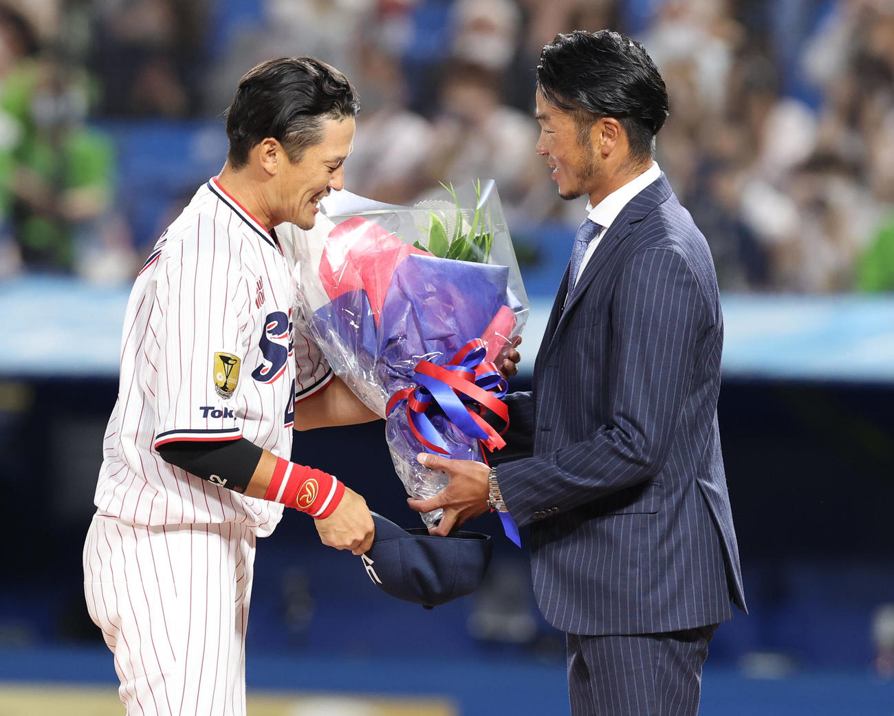 ヤクルト対DeNA　試合後の引退セレモニーでサプライズゲストの近藤一樹氏（右）から花束を受け取る坂口（撮影・狩俣裕三）