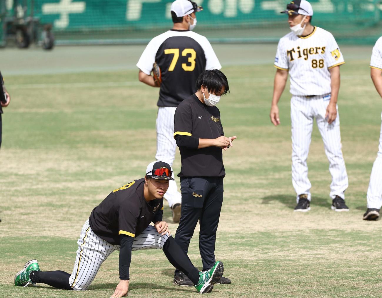 ストレッチして体をほぐす佐藤輝（左）。右は矢野監督（撮影・上田博志）