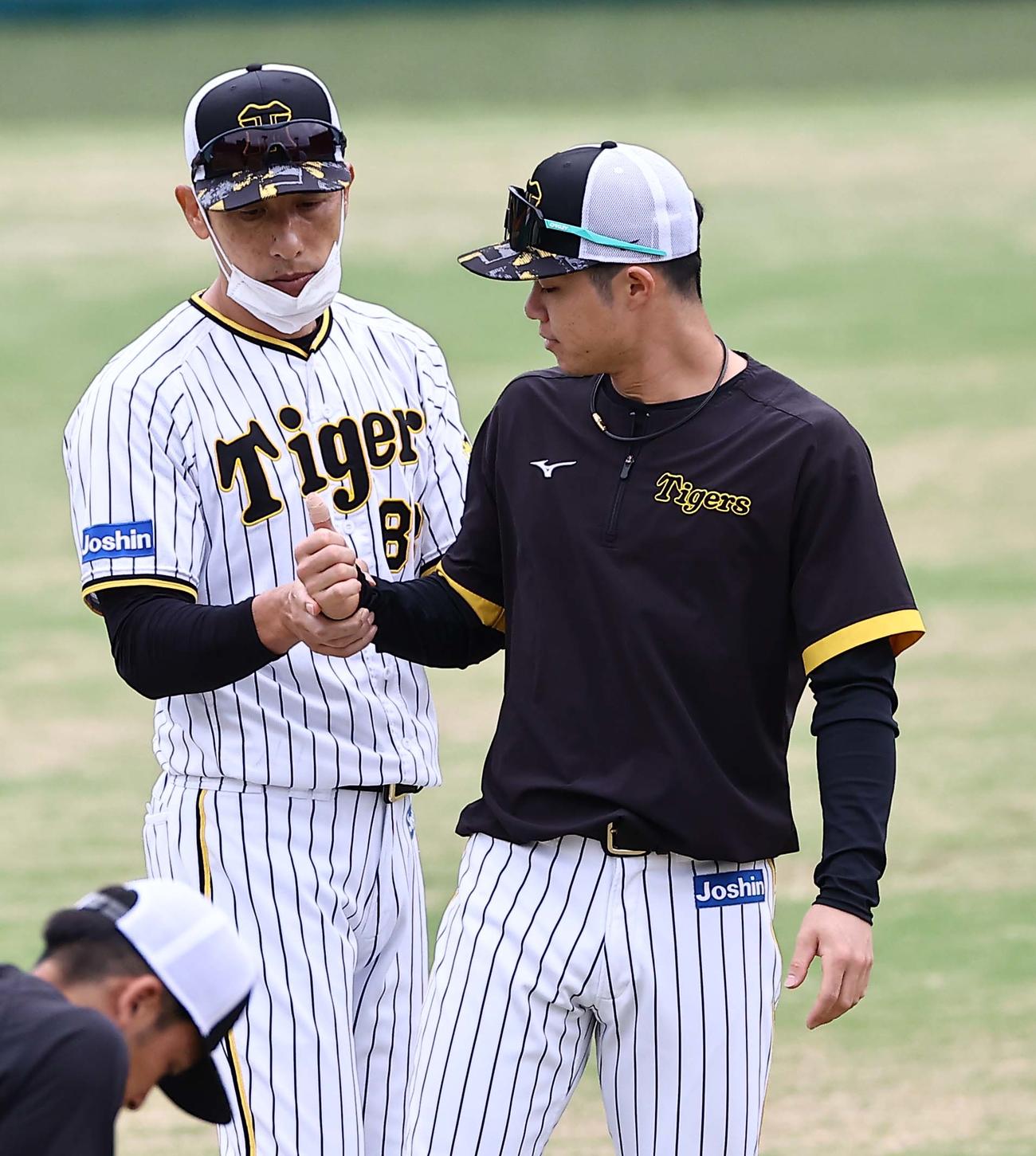 中野（右）のテーピングの巻かれた親指を見つめる矢野監督（撮影・上田博志）