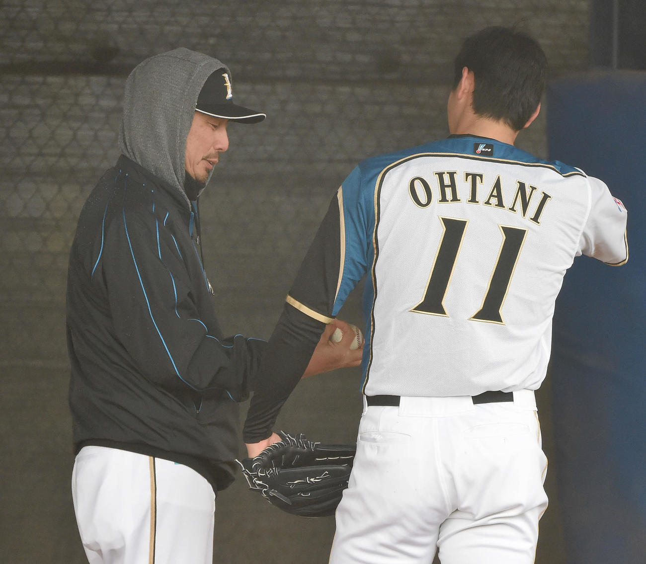 2016年2月1日、キャンプ初日、日本ハム大谷翔平は、チェンジアップの握りを見せながら話す吉井理人投手コーチ（左）のアドバイスを聞く