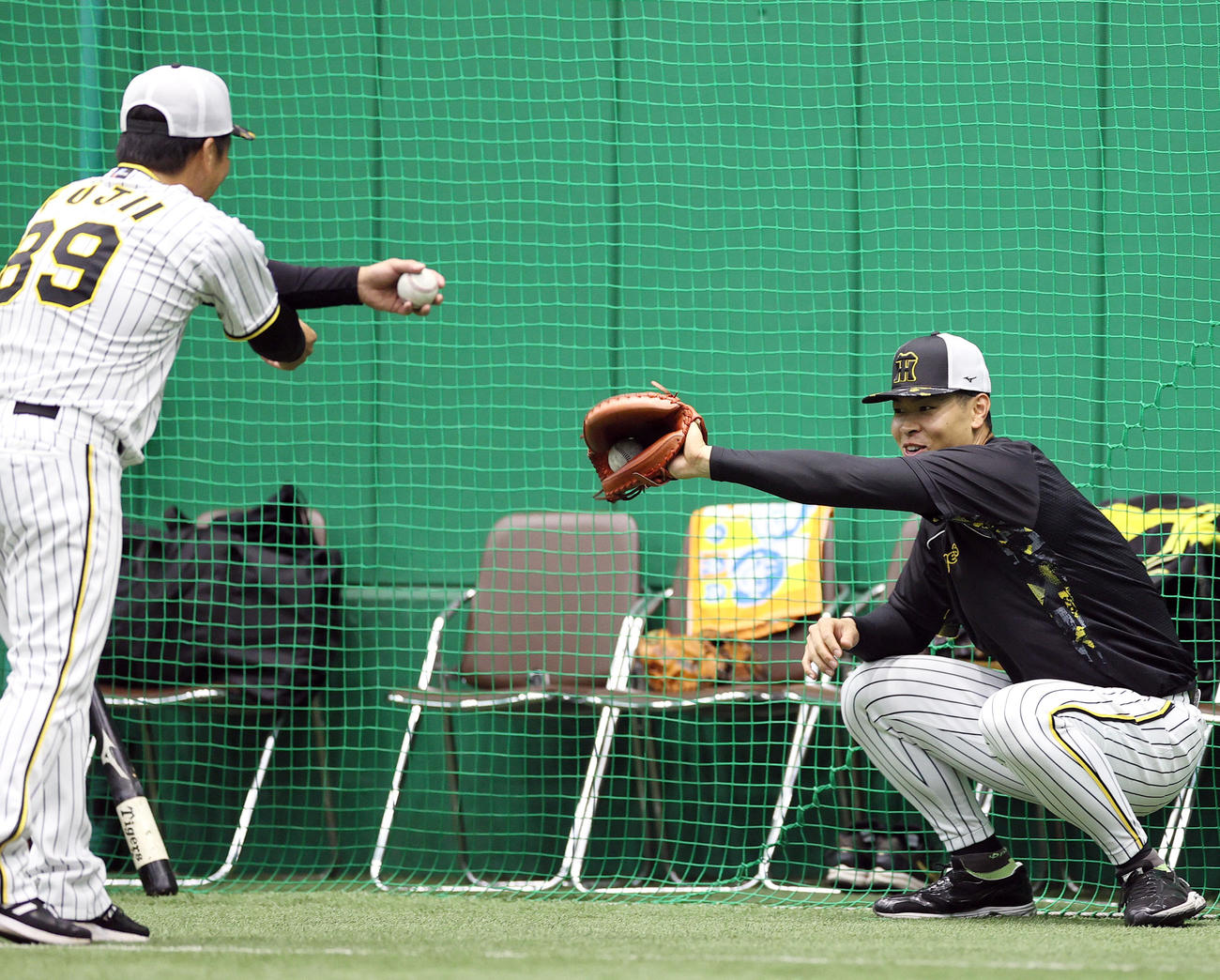 室内で阪神佐藤輝（右）はキャッチャーミットをつけ藤井彰バッテリーコーチの球を受ける（撮影・上山淳一）