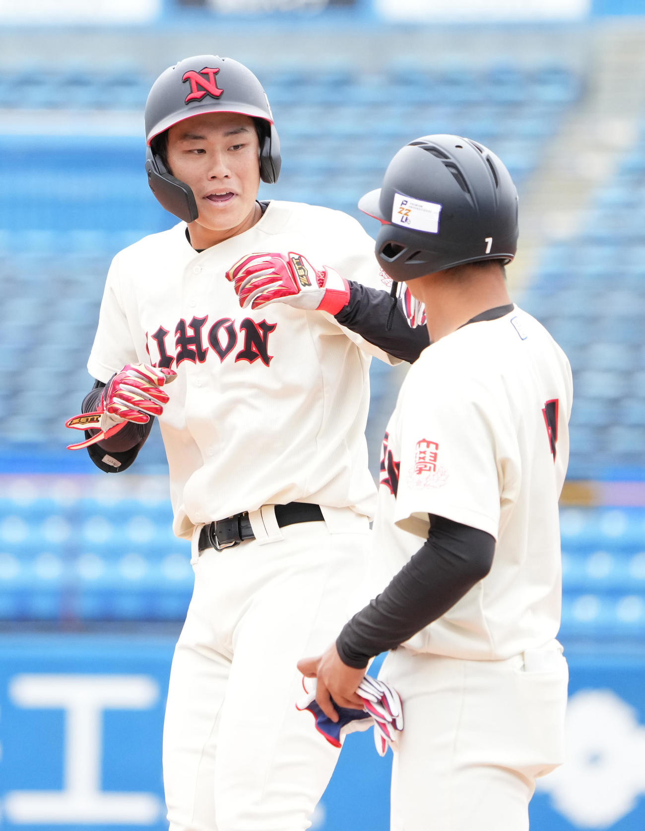 日大対国学院大　7回表日大無死三塁、花崎（左）は中前に勝ち越し適時打を放ち一塁コーチの祝福を受ける（撮影・小沢裕）　