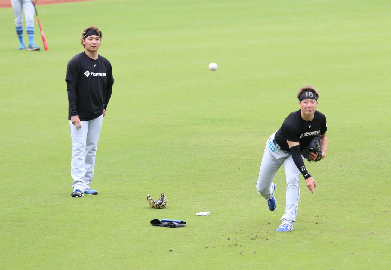 鎌ケ谷で日本ハム伊藤（左）からスライダーを教わる吉田（撮影・木下大輔）