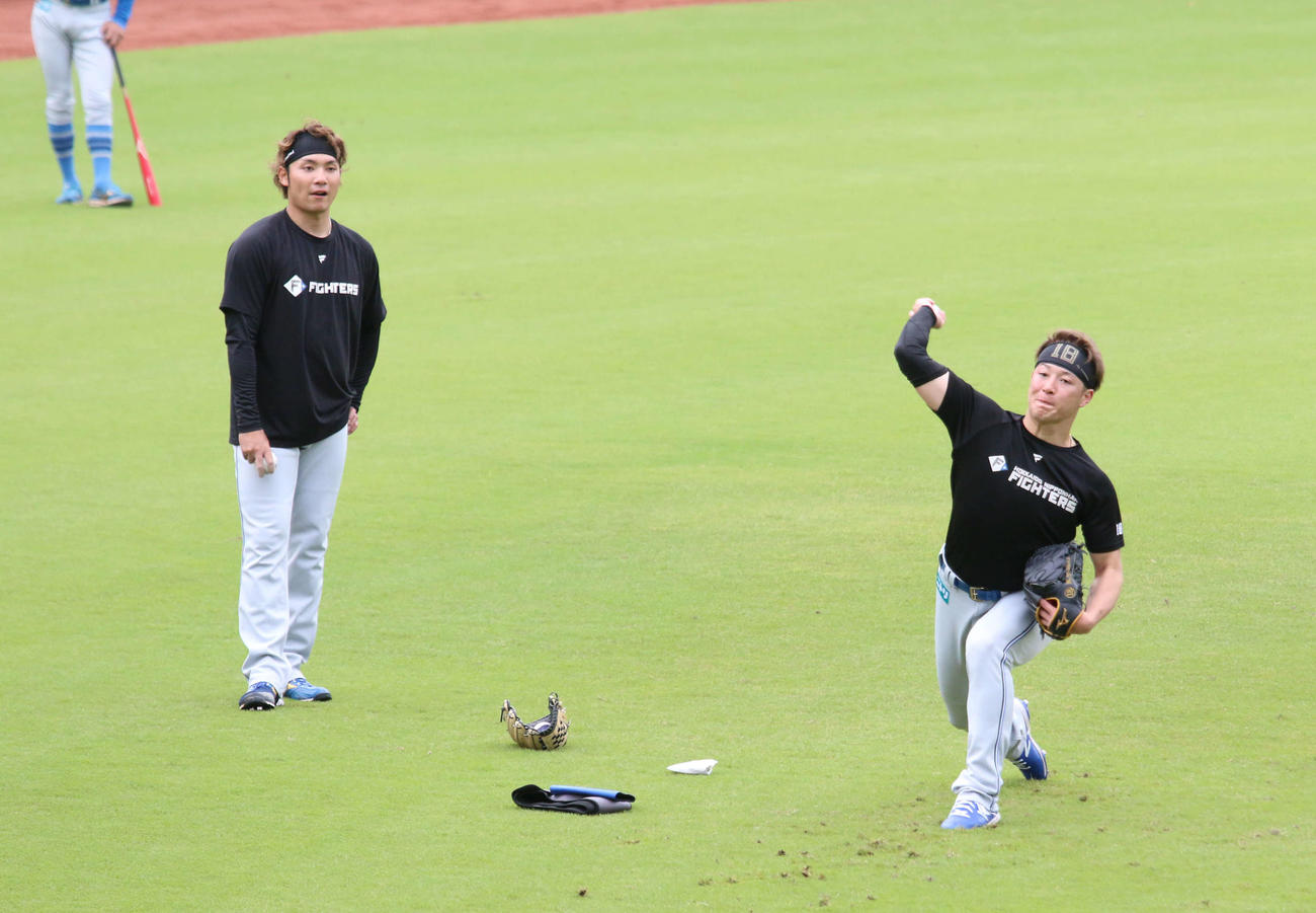 鎌ケ谷で日本ハム伊藤（左）からスライダーを教わる吉田（撮影・木下大輔）