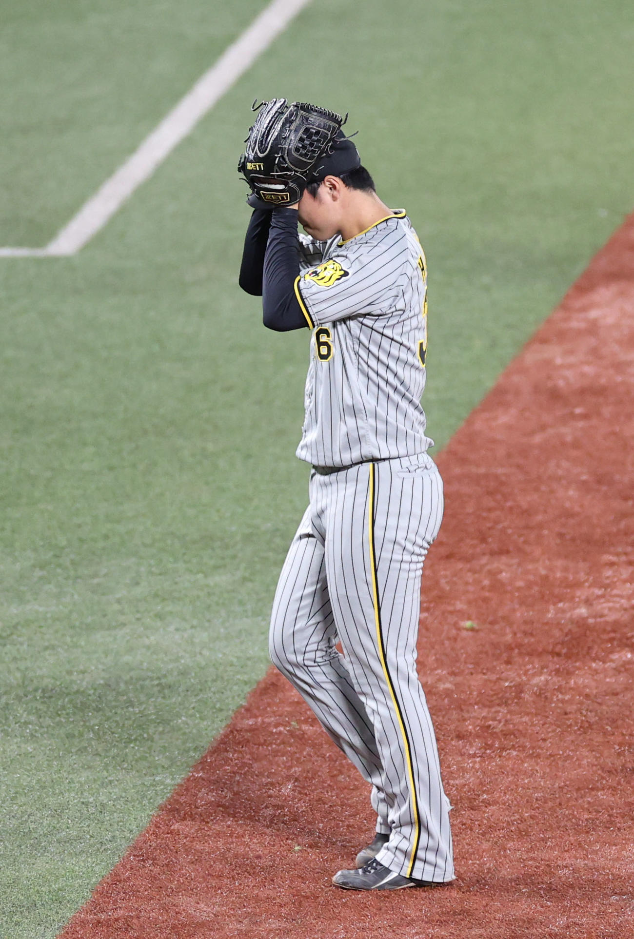 ヤクルト対阪神　7回裏を終え、頭を抱えながらベンチに戻る浜地（撮影・狩俣裕三）