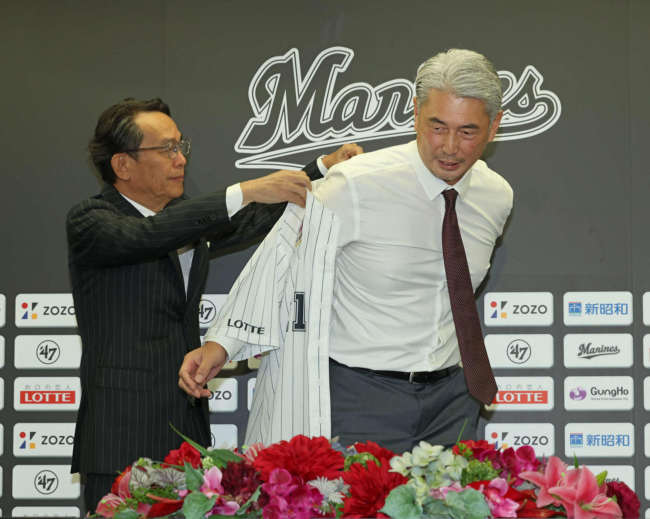 河合球団社長兼オーナー代行（左）からユニホームを着せてもらうロッテ吉井新監督（撮影・丹羽敏通）