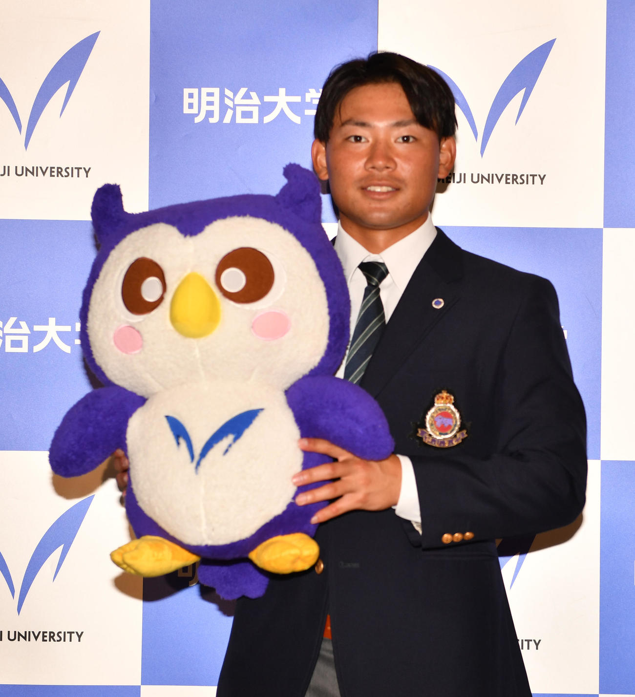 ドラフトで中日2位の明大・村松は明大グッズめいじろうを持ち笑顔を見せる（撮影・柴田隆二）