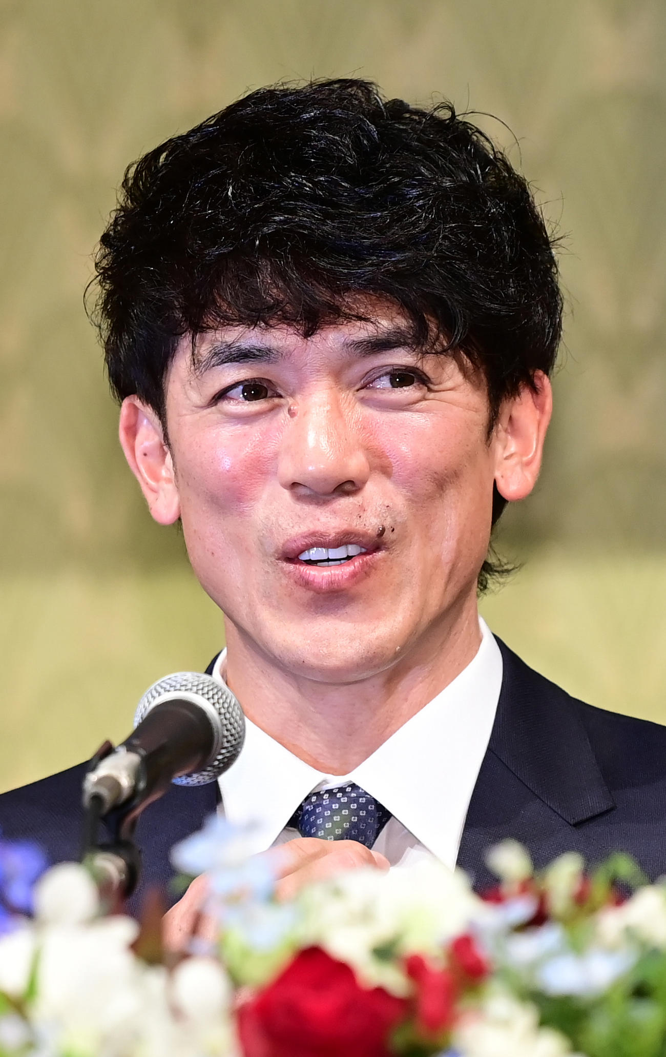 就任会見で着用したライオンズブルーのネクタイに手を添えて笑顔を見せる西武松井新監督（撮影・小沢裕）　
