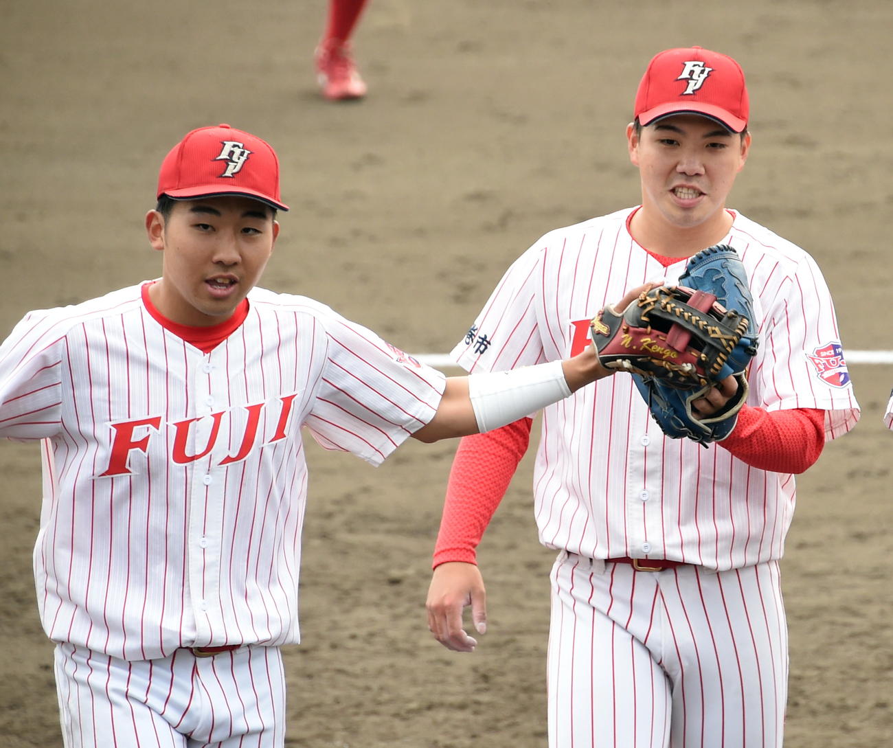 5月21日の青森大戦でグラブタッチする富士大・金村尚真（右）と野原