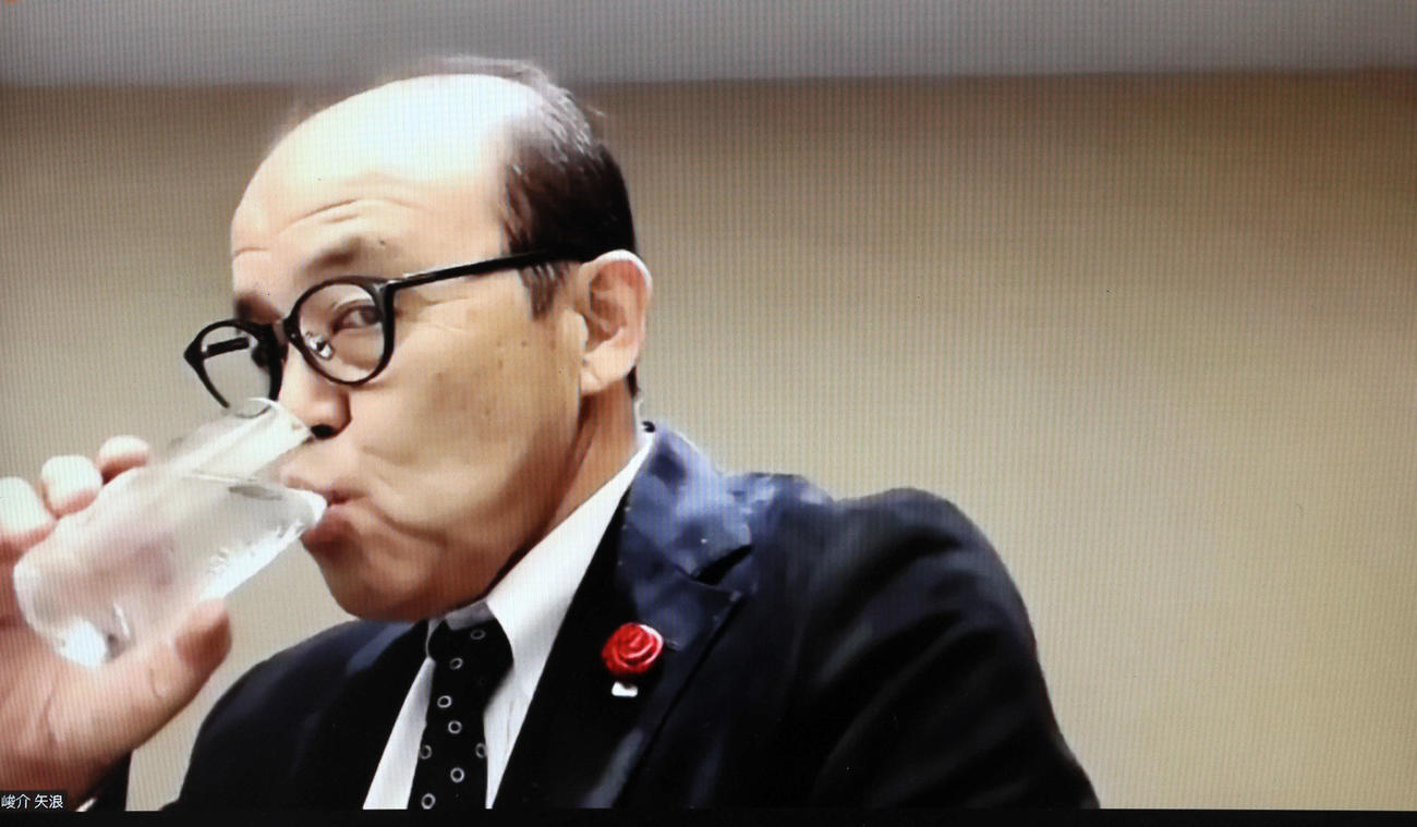ドラフト前日の会議を終えリモート会見した阪神岡田監督は右手で水を飲む