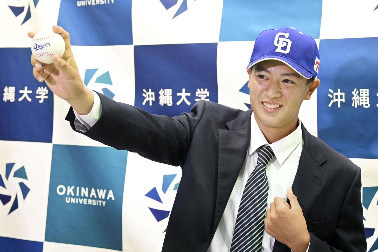 中日から1位指名を受け、ボールを手にポーズをとる沖縄大・仲地（共同）
