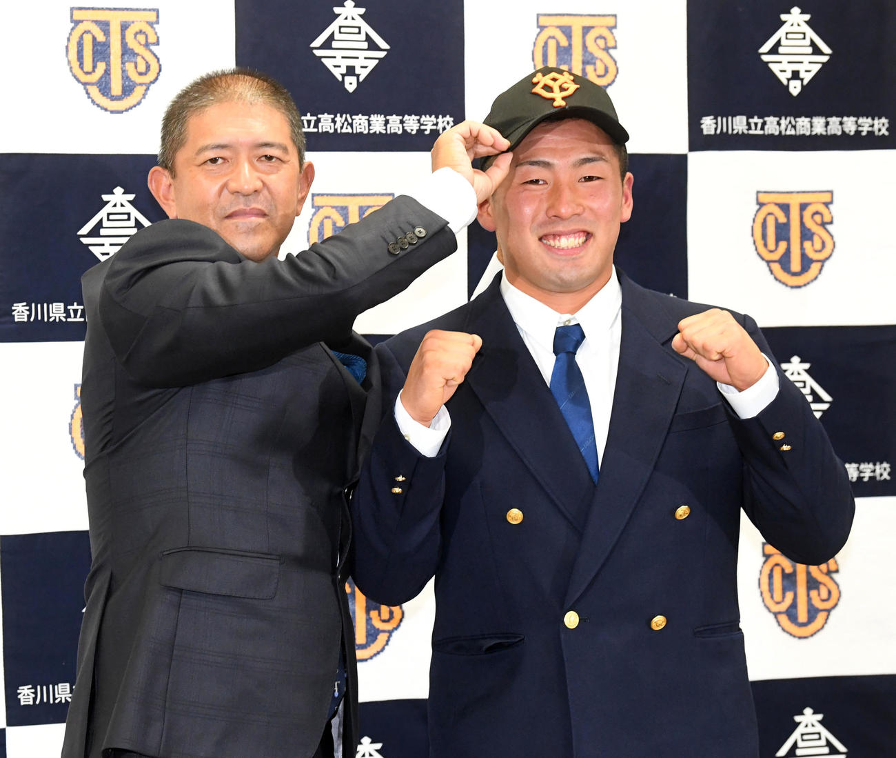 ドラフトで巨人に1位指名された高松商・浅野（右）は長尾監督から巨人の帽子をかぶせてもらう（撮影・前岡正明）