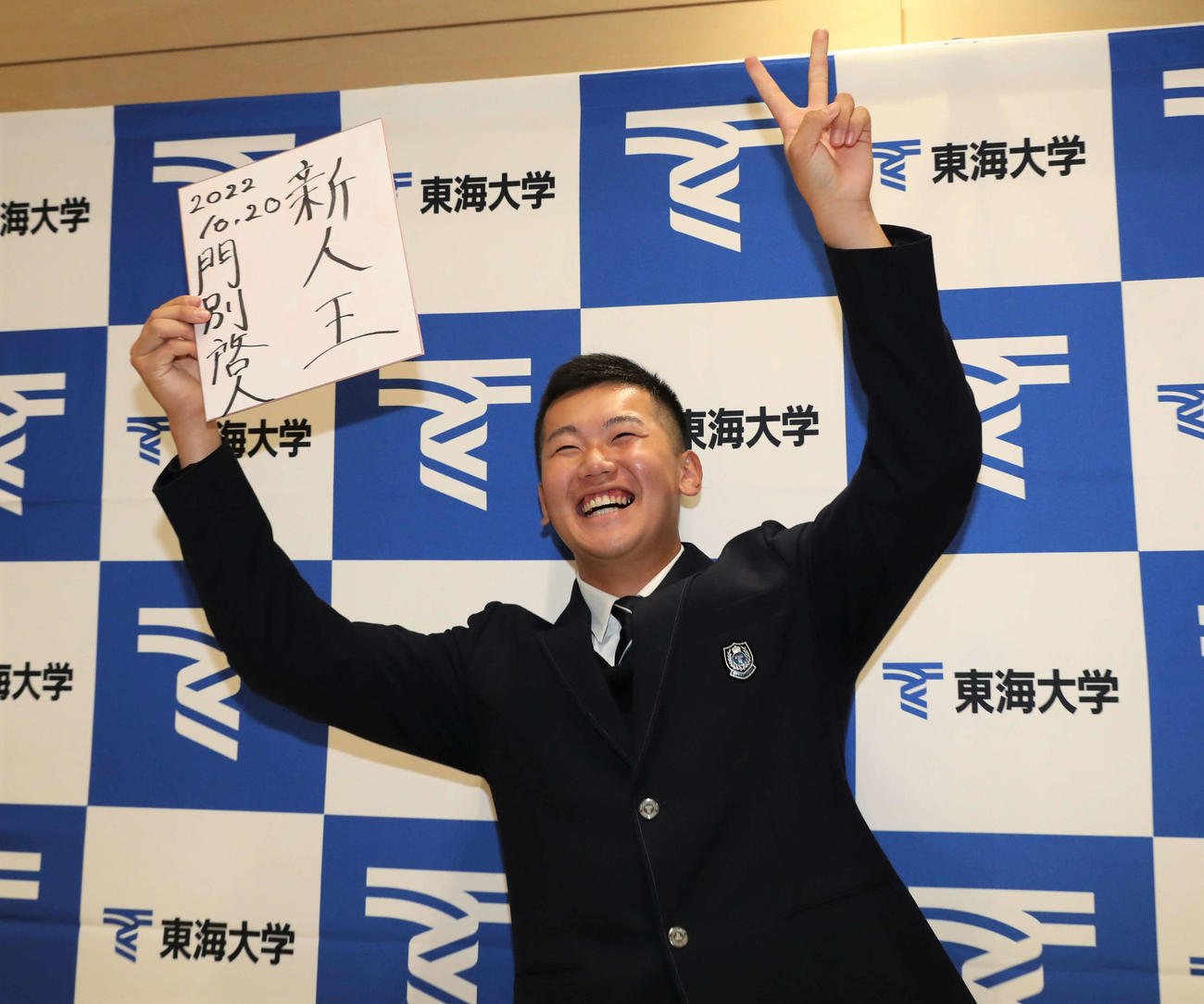 阪神から2位指名された東海大札幌の門別はプロでの抱負を色紙に書き笑顔を見せる（撮影・黒川智章）