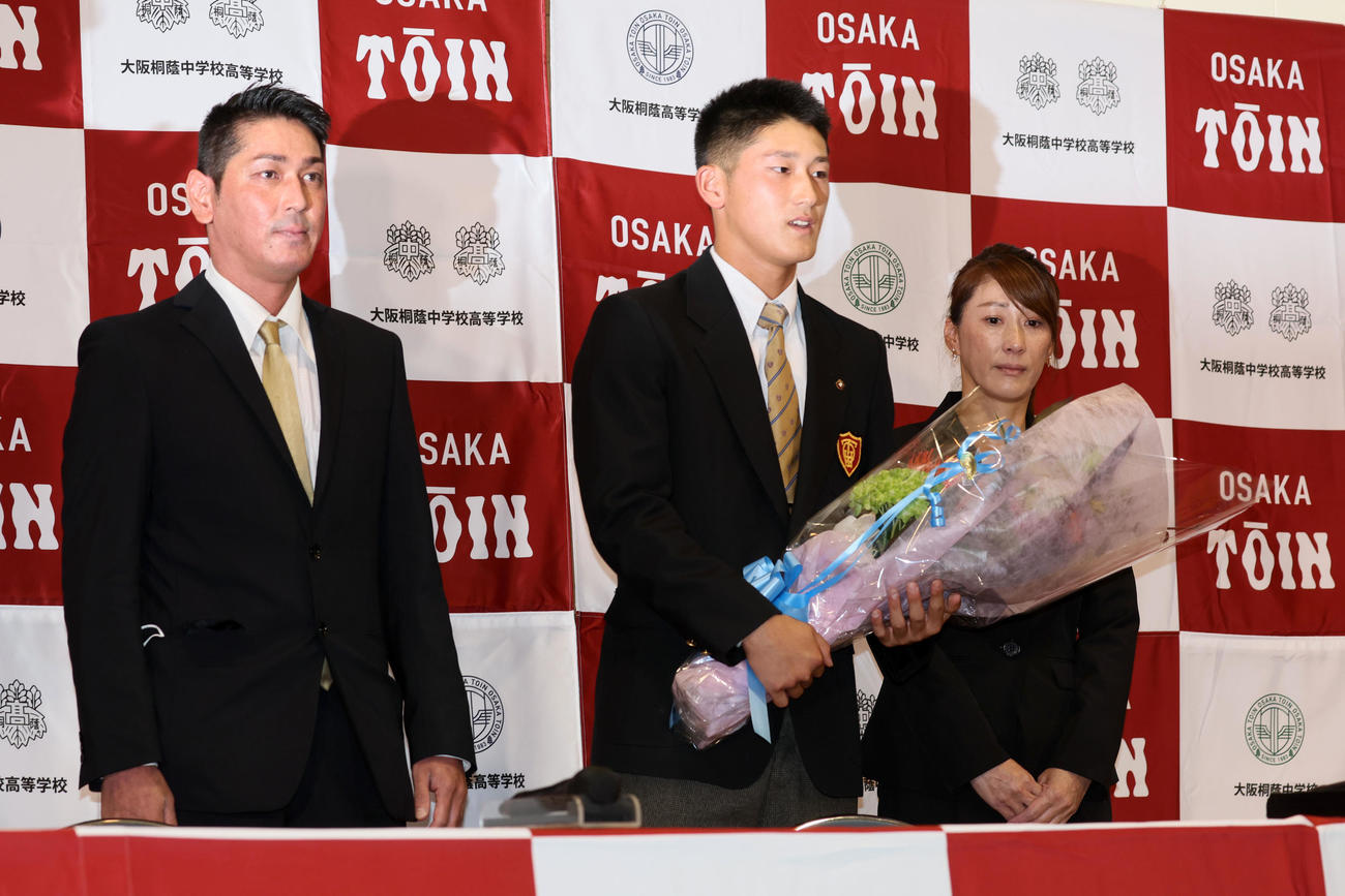 DeNAから1位指名を受け花束を手に両親と記念写真に納まる大阪桐蔭の松尾（撮影・加藤哉）