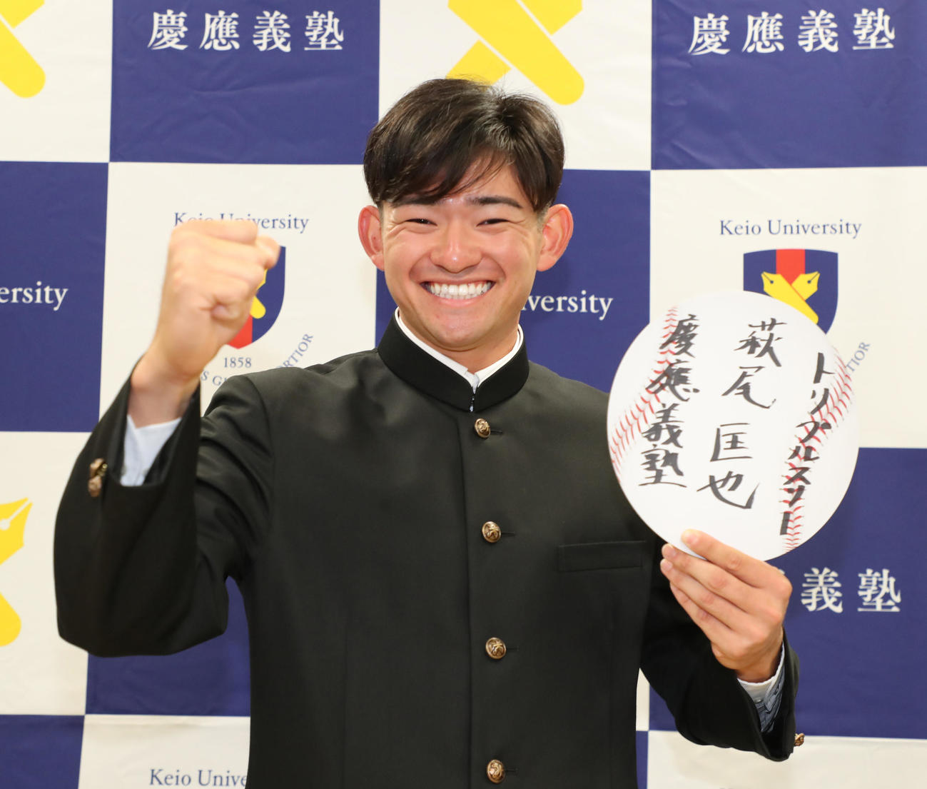 巨人から指名を受け目標を書いた色紙を手に笑顔の慶大・萩尾（代表撮影）