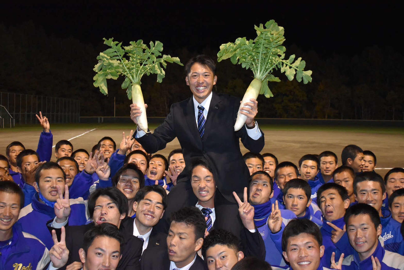 楽天から4位で指名された東農大北海道オホーツク・伊藤は大根を手に笑顔を見せる（同校提供）