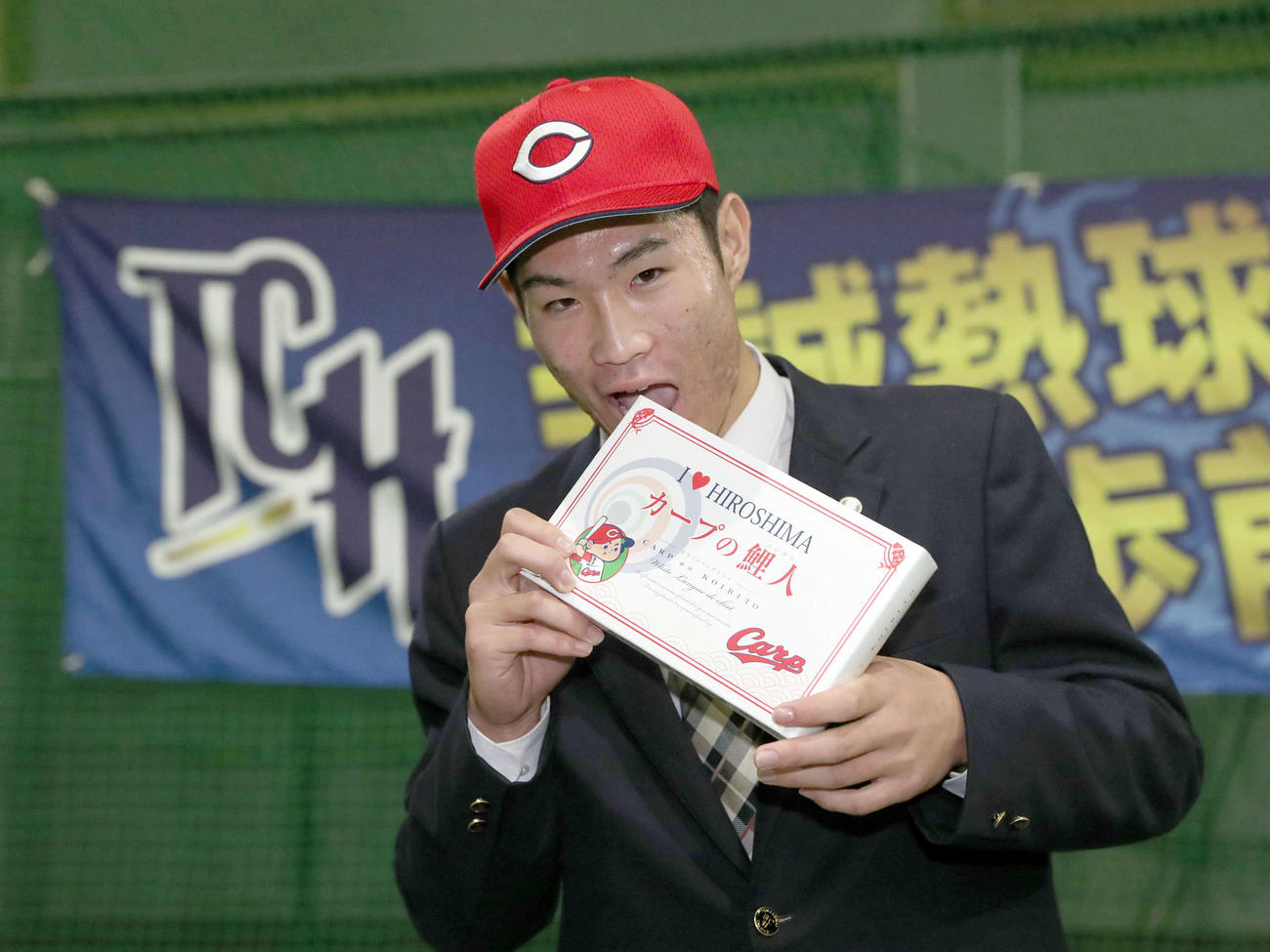 広島からドラフト1位指名を受けた苫小牧中央の斉藤はカープの鯉人を食べる素振りをする（撮影・佐藤翔太）