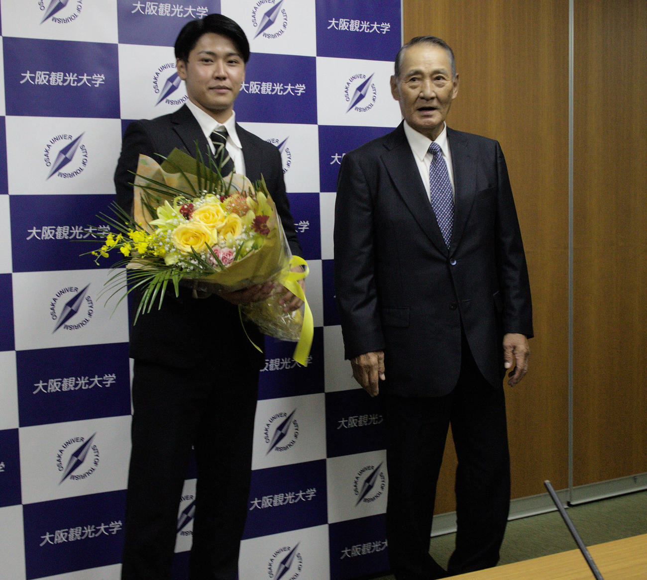 広島7位指名を受けた大阪観光大・久保（左）と同大学の特別アドバイザー伊勢孝夫氏（撮影・桝井聡）