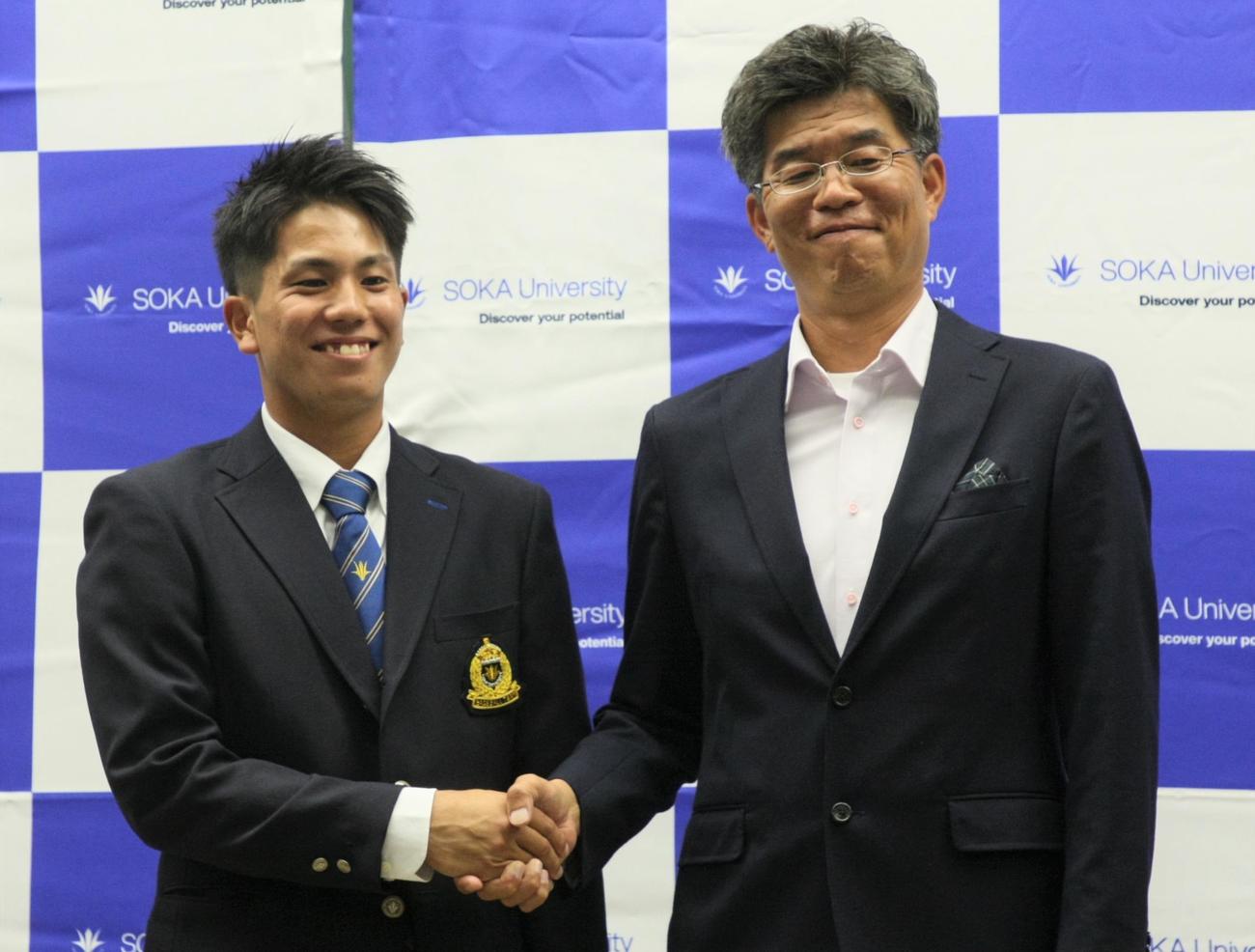 巨人から4位指名を受けて笑顔を見せる創価大・門脇（左）と父寿光さん（撮影・藤塚大輔）