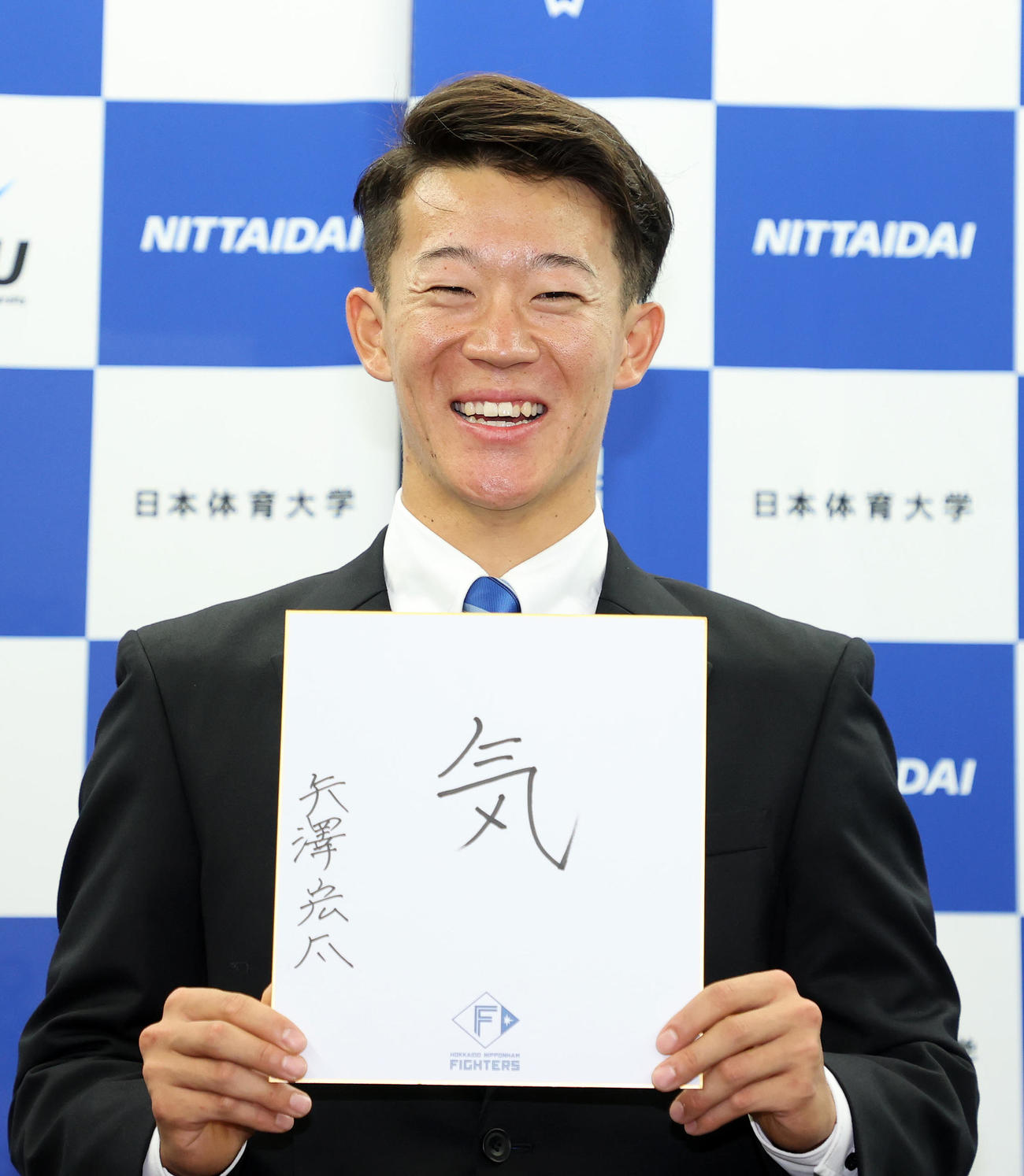 色紙に「気」と書き笑顔を見せる日体大・矢沢（撮影・鈴木正人）