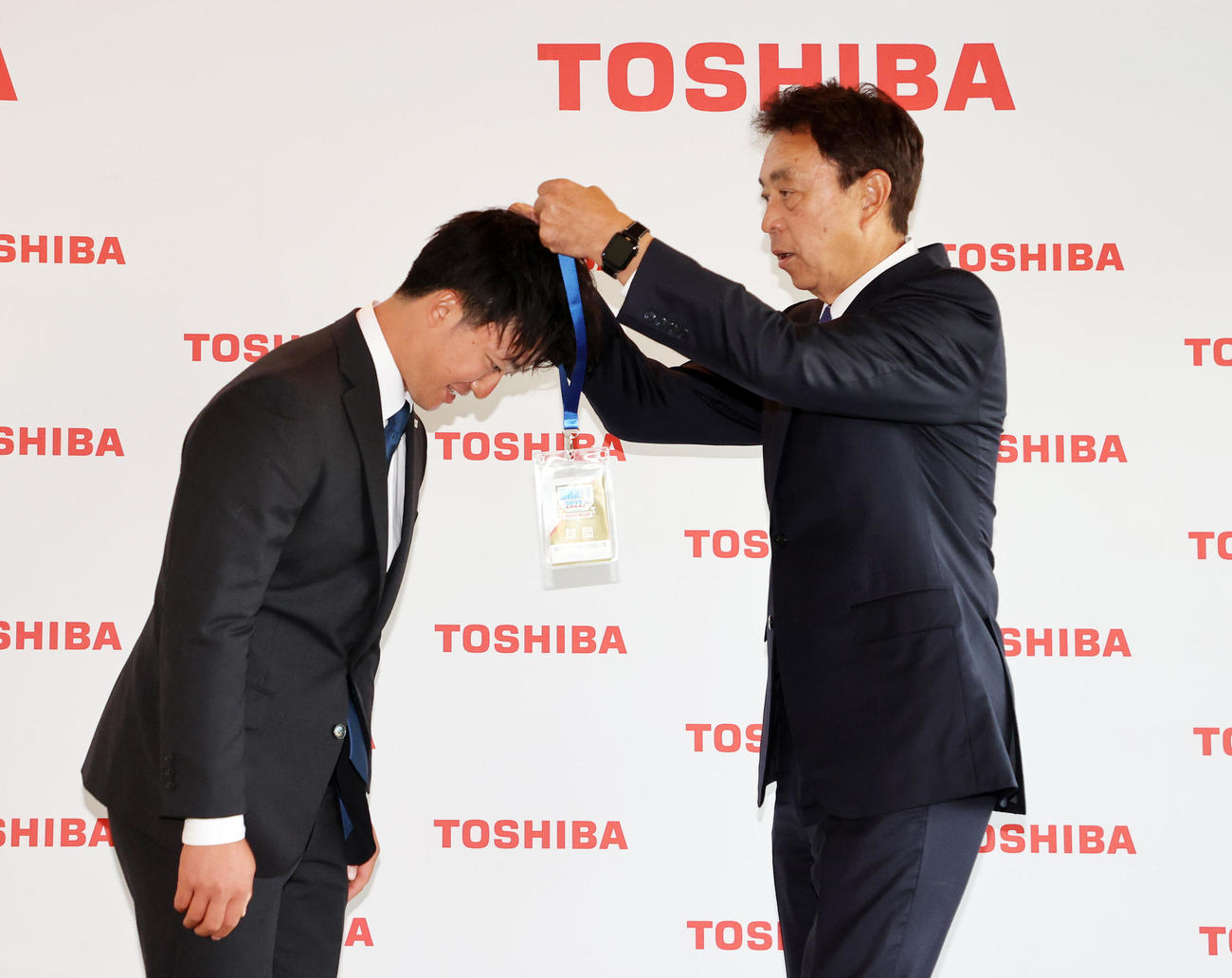 ヤクルト高津監督からメッセージ入りのIDを小川GM（右）から首にかけてもらう東芝・吉村（撮影・鈴木正人）