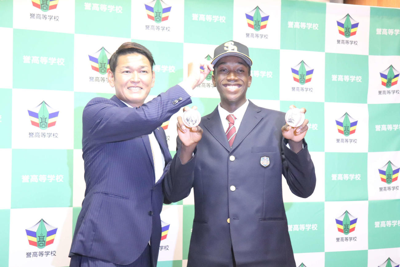 ソフトバンクの指名あいさつを受けた誉のイヒネ・イツアは同球団の永井編成育成本部本部長兼スカウト部部長と笑顔