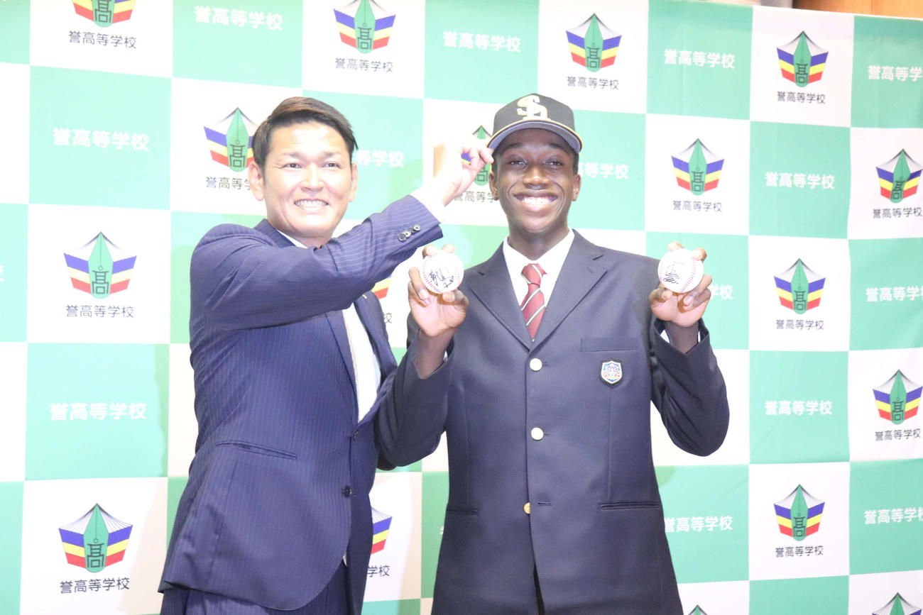 ソフトバンクの指名あいさつを受けた誉のイヒネ・イツアは同球団の永井編成育成本部本部長兼スカウト部部長と笑顔