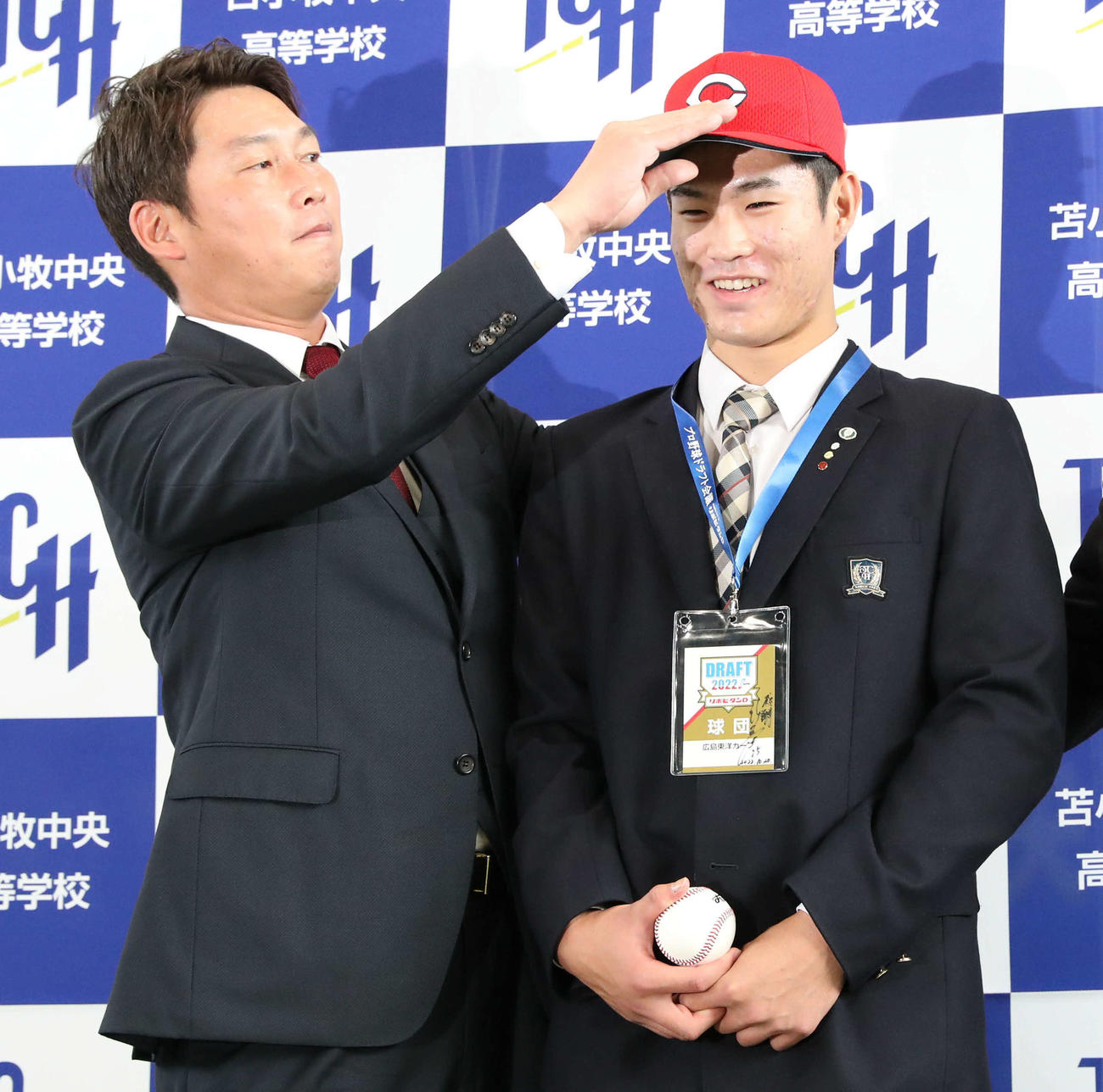 広島新井新監督（左）はドラフト1位指名をした苫小牧中央の斉藤の帽子を直す（撮影・佐藤翔太）