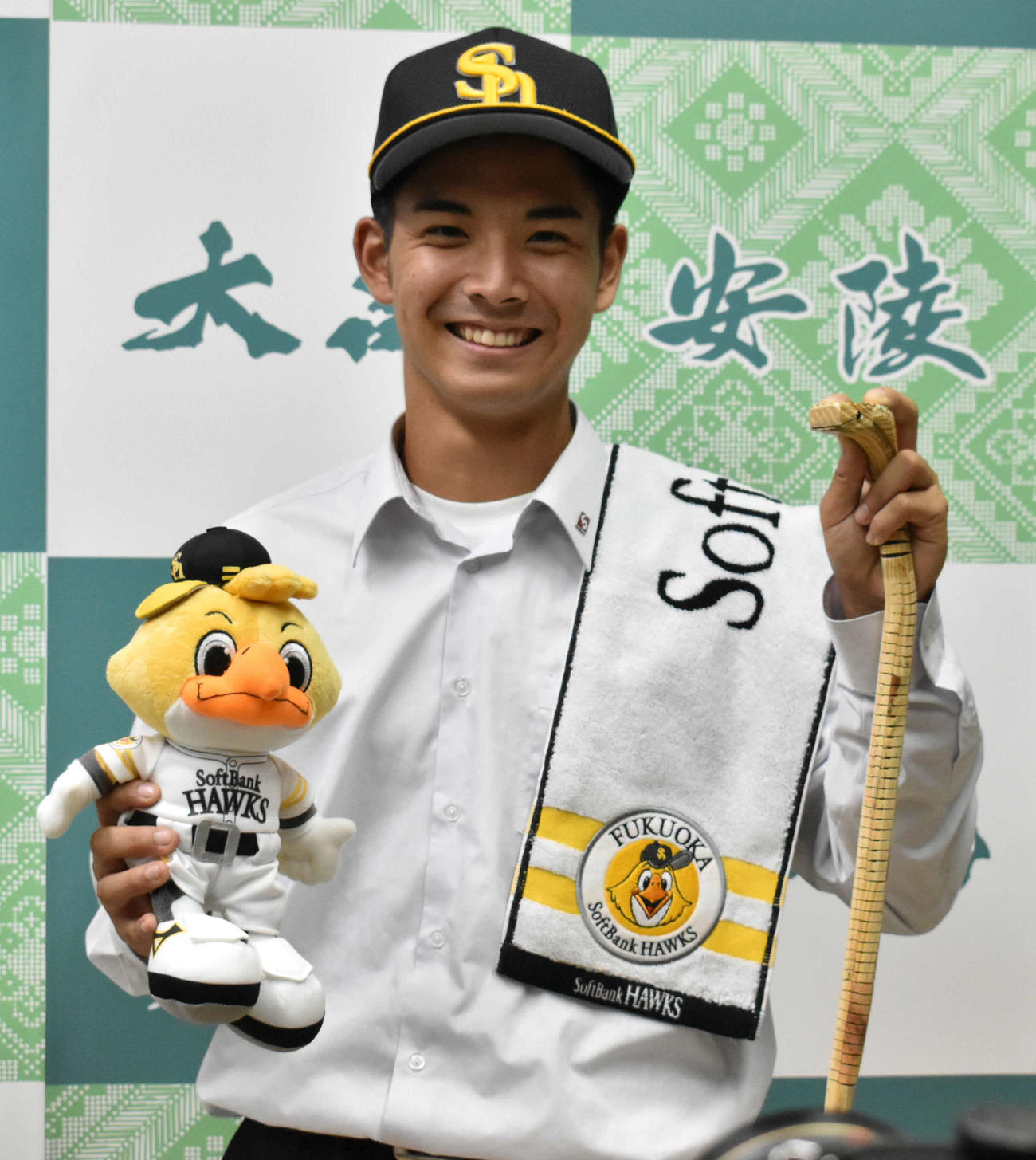 球団グッズと奄美大島に数多く生息するヘビのおもちゃを持って笑顔を見せる大島・大野稼頭央（撮影・只松憲）