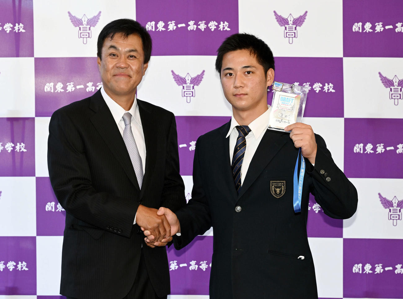 受け取った阪神岡田監督のサインが入ったドラフト会議のパスを手に平塚スカウト（左）と写真に納まるドラフト3位の関東第一・井坪（撮影・滝沢徹郎）　