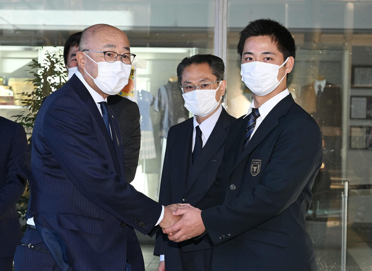 指名あいさつに訪れた阪神畑山統括スカウト（左手前）と握手を交わすドラフト3位の関東第一・井坪（撮影・滝沢徹郎）　