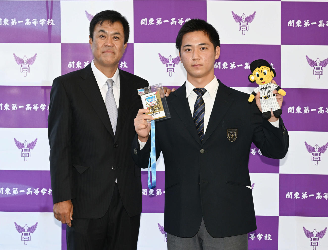 受け取った阪神岡田監督のサインが入ったドラフト会議のパスとトラッキーの人形を手にポーズを決めるドラフト3位の関東第一・井坪（右）と平塚スカウト（撮影・滝沢徹郎）　