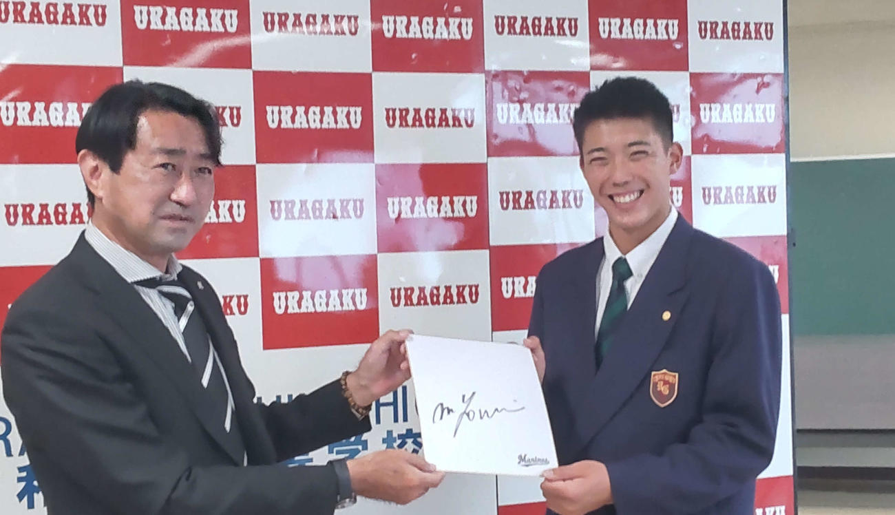 指名あいさつを受けたロッテのドラフト5位、浦和学院・金田優太内野手（右）は中川隆治スカウトらから吉井理人新監督のサイン色紙を渡され、にっこり