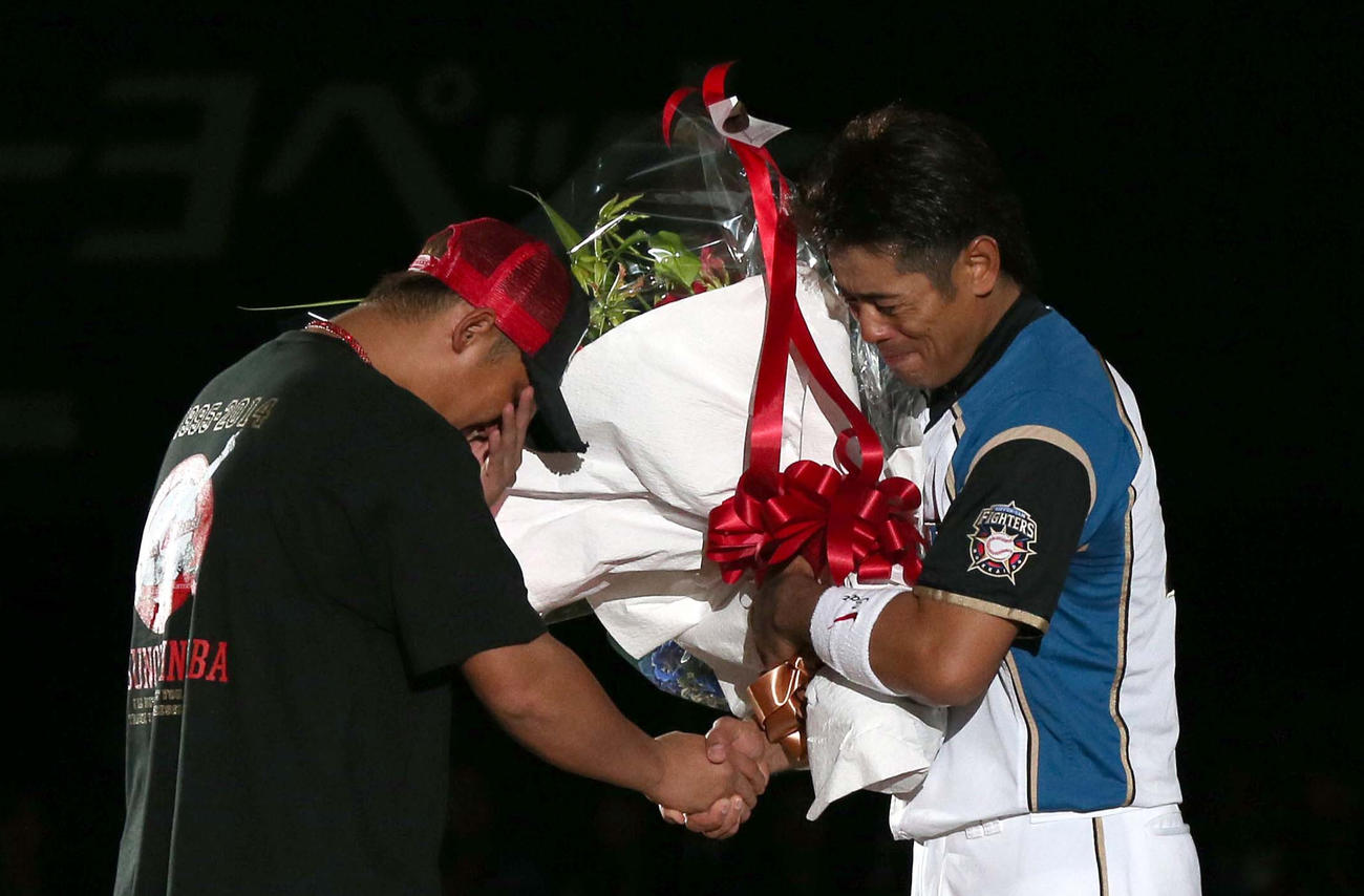 14年10月、引退セレモニーで中田から花束を受け取る稲葉