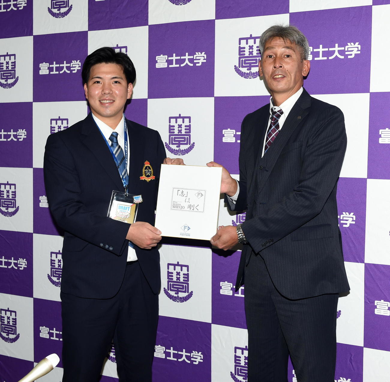 指名あいさつを受け新庄剛志監督の特製スタンプが押された色紙を持って記念撮影する日本ハムのドラフト2位・富士大・金村（左）と白井スカウト（撮影・山田愛斗）