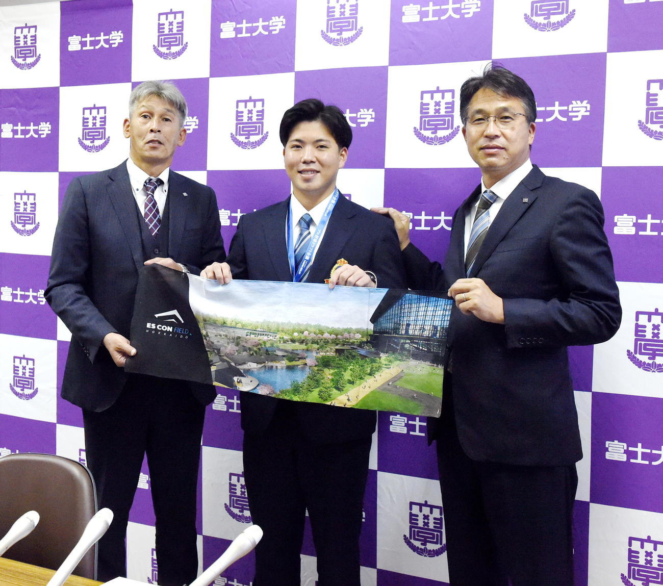 指名あいさつを受け新球場がプリントされたタオルを持って記念撮影する日本ハムのドラフト2位・富士大・金村（中央）。左は白井スカウト、右は大渕GM補佐兼スカウト部長（撮影・山田愛斗）