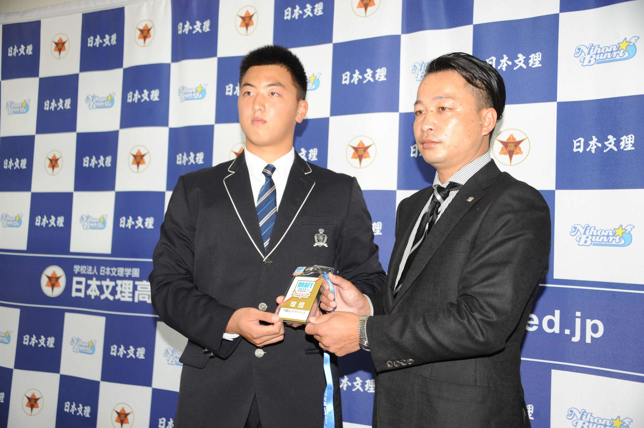 ドラフト会議のパスを小林スカウトから手渡される日本文理・田中