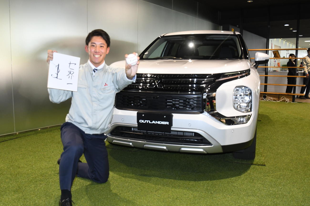 三菱製の自動車をバックに笑顔で記念撮影する三菱自動車岡崎・富田蓮（撮影・中野椋）