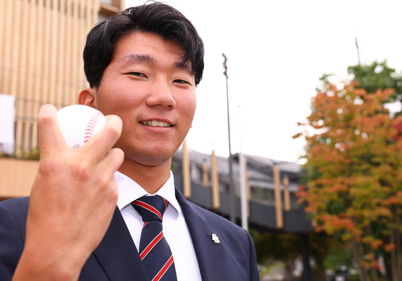 巨人から指名あいさつを受け、ボールを手に笑顔を見せる国学院大・田中千晴（撮影・垰建太）
