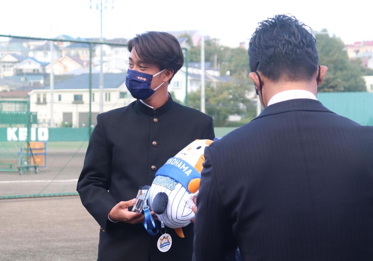 DeNAから指名あいさつを受けた慶大・橋本（奥）は、プレゼントを手に笑顔をみせる（撮影・阿部泰斉）